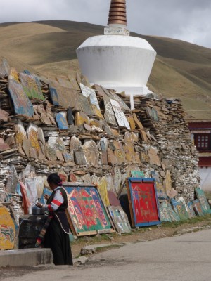 Tibetan woman walking past stupa in Litang Tibet